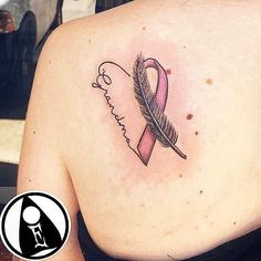 a woman with a tattoo on her back has a pink ribbon and a key