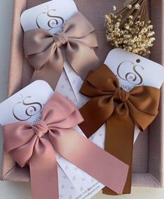 three different colored bows in a box with some flowers on the top and one is brown