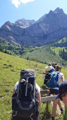 several people with backpacks are sitting on a bench looking at the mountains and valleys