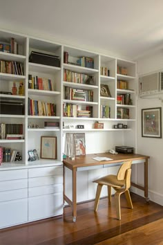 an office with white bookcases and wooden floors