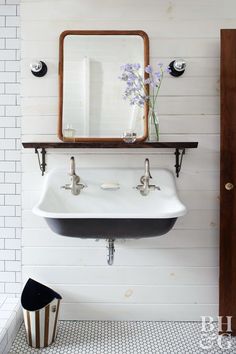 a white sink sitting under a mirror next to a wooden framed mirror on a wall