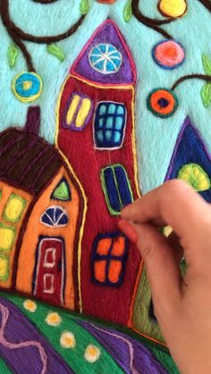 someone is drawing something with colored crayons on the paper that looks like houses