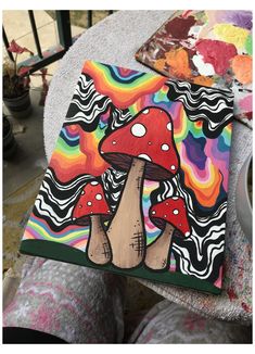 someone is holding up a colorful mushroom painting