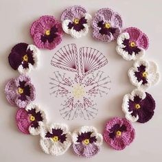 crocheted flowers arranged in a circle on top of a white surface with yellow and purple centers