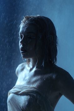 a woman standing in the rain with her hands on her hips and head tilted back