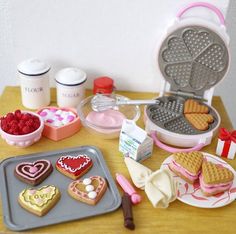 a table topped with heart shaped cookies next to a waffle maker and other items