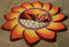 a large flower shaped rug on the ground with flowers and other items in it's center