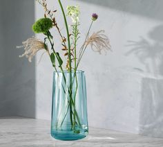 there is a vase with flowers in it on the table next to a white wall