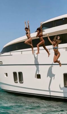 three women jumping off the side of a boat