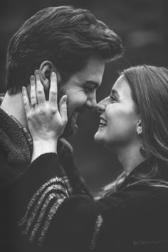 black and white photo of two people smiling at each other with their hands on their faces