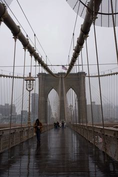 people walking across a bridge in the rain