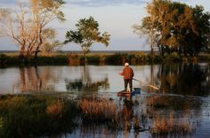 a man standing on top of a boat in a river