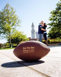 a football laying on the ground in front of a building with a couple standing next to it