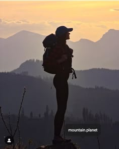 a person standing on top of a mountain with a backpack in their hands and the sun setting behind them