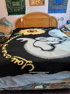 a bed with a mickey mouse blanket on it's head and some pictures above it