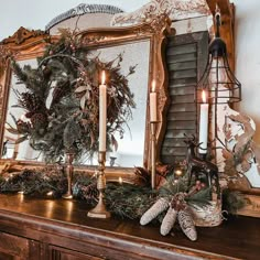 a mantle with candles, wreaths and other christmas decorations on it in front of a mirror