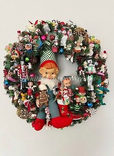 a christmas wreath hanging on the wall with ornaments around it and a small teddy bear