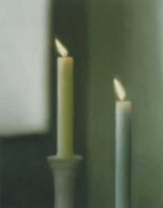 two lit candles sitting next to each other on a table