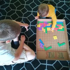 two boys playing with a board game on the floor