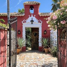 an entrance to a pink house with potted plants on either side and a door in the middle