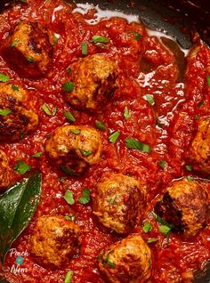 meatballs and sauce in a skillet ready to be cooked with green leafy garnish