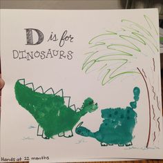 a child's hand holding up a drawing of a dinosaur