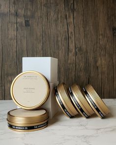 four gold colored coasters sitting next to each other on a marble counter top with a white box in the background