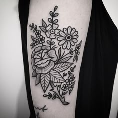 a black and white flower tattoo on the right upper half of the arm, with leaves and flowers around it