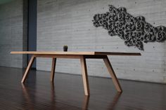 a wooden table sitting on top of a hard wood floor next to a brick wall