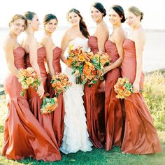 a group of women standing next to each other wearing dresses and holding bouquets in their hands