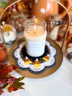 a candle is sitting on a plate next to some pumpkins