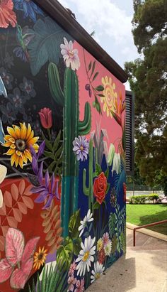 a colorful mural on the side of a building with cactus and flowers painted on it