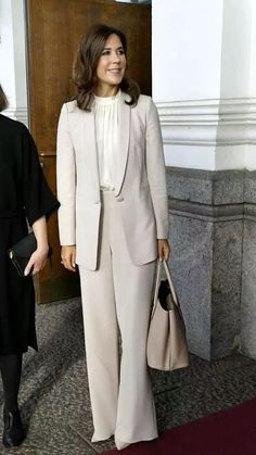 the woman is walking down the red carpet with her hand in her pockets and wearing a white suit