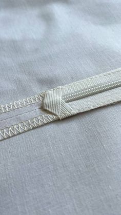 a close up of the zippers on an unmade bed sheet with white thread