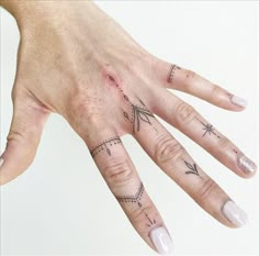 a woman's hand with three different tattoos on her left thumb and one finger