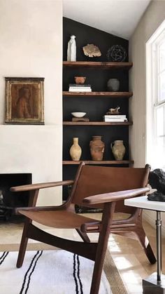 a chair sitting in front of a fire place next to a book shelf filled with books