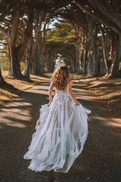 a woman in a white dress is walking down the road with her back to the camera