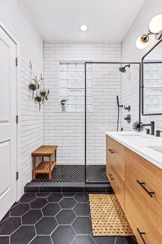 a bathroom with black and white tile flooring, wooden cabinets and a walk in shower