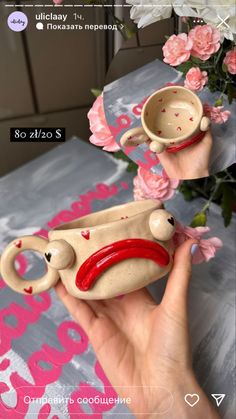 a hand holding a ceramic cup and saucer in front of a vase with flowers