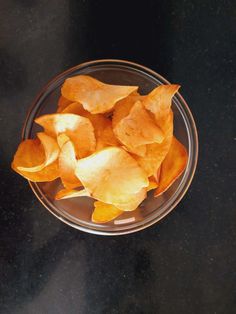 a glass bowl filled with potato chips on top of a table