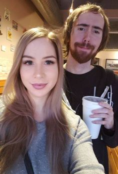 a man and woman taking a selfie in a coffee shop with one holding a cup