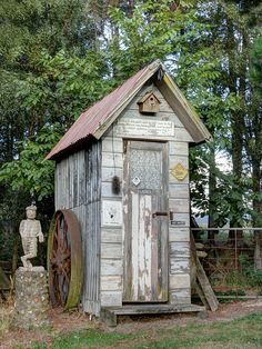 an outhouse in the woods with a water wheel on it's front door