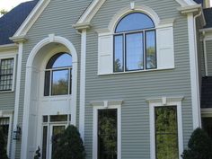 a large gray house with white trim and arched windows