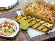 some food is sitting on top of a wooden cutting board next to a bowl and plate