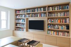 a living room filled with furniture and a flat screen tv mounted on a wooden book shelf