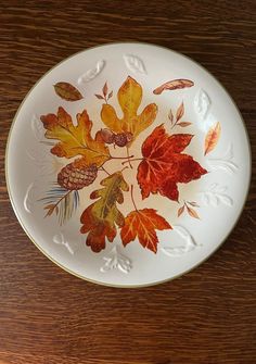 a white plate with autumn leaves painted on it