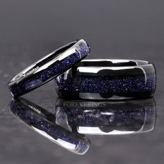 two wedding bands with blue glitter on them, one is black and the other is silver