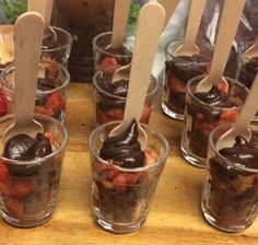 chocolate desserts in plastic cups with wooden spoons on a wood table, ready to be eaten