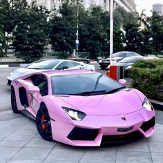 a pink sports car is parked in front of a white building with columns and pillars