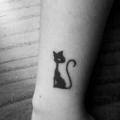 a small black cat tattoo on the ankle